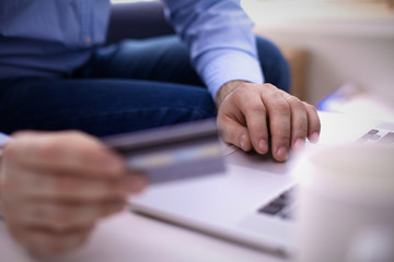 Obraz premium Businessman sitting at table with laptop and documents