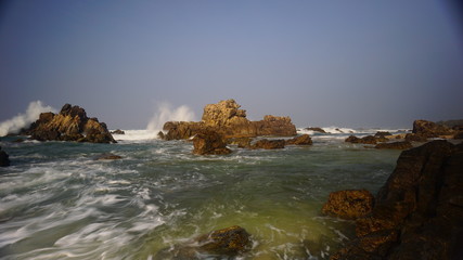 The splashing sea water in the red rock Karang Beureum beach, anten Province