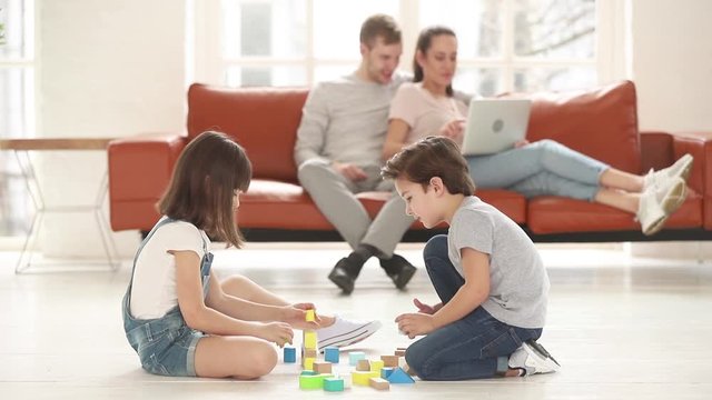 Kids playing with toy blocks set sitting on warm floor