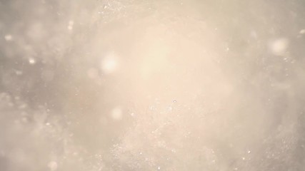 submerged in a blender filled with crushed ice cubes & water, pushing towards ice as particles in water float around. Lights at the end flair into abstract patterns.