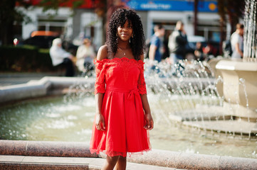 Stylish trendy afro france curly woman posed at autumn day in red dress. Black african female model...
