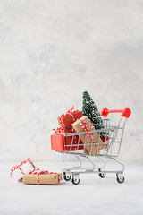 Shopping cart full of gift boxes and a Christmas tree.
