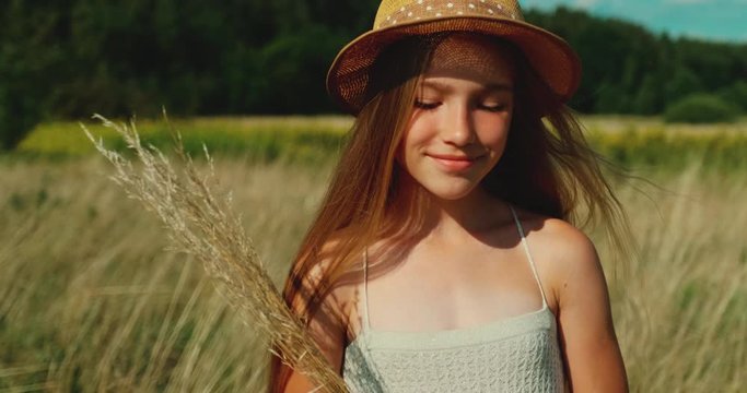 Cheerful girl in hat walking in the field. Close Up portrait. Slow motion