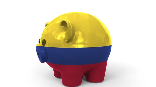 Coins fall into piggy bank painted with flag of Colombia. National banking system or savings related conceptual 3D animation