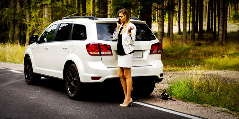 Business woman catched a flat tire and calling for car assistance. Car insurance.