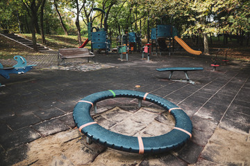 Colorful children's playground with slides, swings and other objects in a public park with many trees around and no people