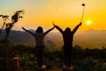 Couple of women friend enjoying morning sunrise on mountain
