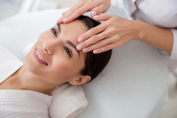 Obraz na płótnie Canvas Charming young woman having face massage at beauty salon