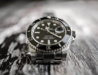 Close-up, shallow focus view of a well-known, Swiss manufactured mechanical diving watch showing detail of the its face, bezel and lettering.