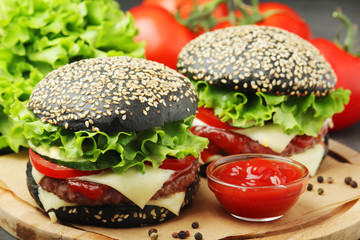 Two black burgers with vegetables and beef meat	