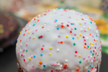 Fototapeta na wymiar Easter spring cake in white glaze with colored sprinkles