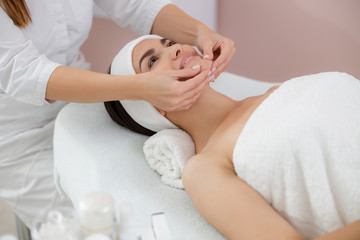 Fototapeta na wymiar Joyful young woman having face massage at spa salon
