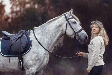 Beautiful girl posing with a purebred arabian horse outdoors. 