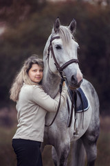 Beautiful girl posing with a purebred arabian horse outdoors. 