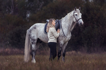 Beautiful girl posing with a purebred arabian horse outdoors. 