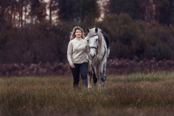 Beautiful girl posing with a purebred arabian horse outdoors. 