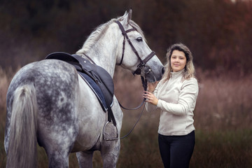 Beautiful girl posing with a purebred arabian horse outdoors. 