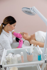 Charming young woman having beauty procedure at spa salon