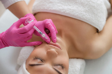 Obraz na płótnie Canvas Young lady getting beauty injection at spa salon