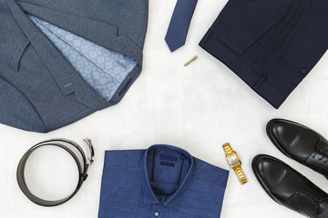Suit jacket, pants, blue shirt, black shoes, belt, watch, necktie, tie clip. Overhead view of...