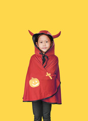 Portrait of little child girl dressed Halloween costume. Kid in Dracula coat isolated over yellow background.