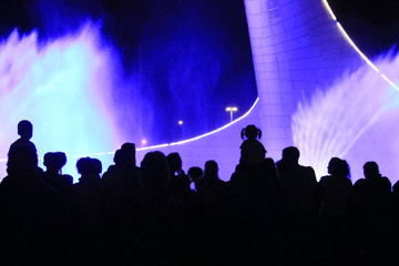 Fototapeta na wymiar Spectators who follow the work of the musical fountain