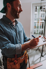 Fototapeta premium Contented construction worker smiling and writing stock photo