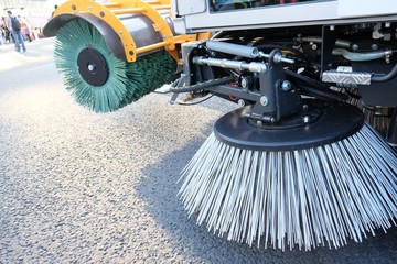 Routine sweeping of municipal streets and highways. Sweeping equipment.Combination of two sweeping brushes of street sweeper close up.