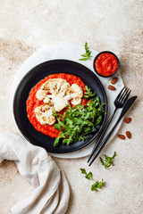 Roasted cauliflower steak with red pepper romesco sauce and arugula salad