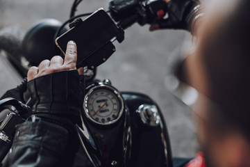 Cropped photo of male biker finding the destination on cell phone