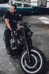 Fototapeta na wymiar Caucasian adult biker spending time in garage