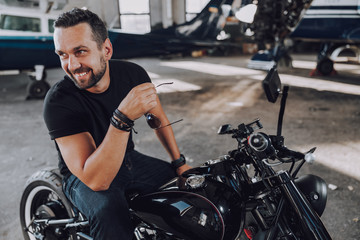 Fototapeta na wymiar Caucasian smiling biker having fun in garage