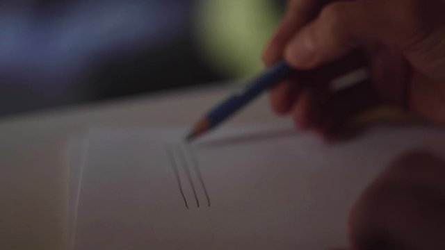 close up su mano che disegna uno spartito musicale con una matita su un foglio di carta