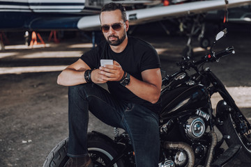 Fototapeta na wymiar Calm man chatting online in garage on his motorbike