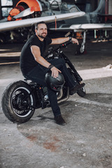 Fototapeta na wymiar Smiling Caucasian guy waiting for somebody on modern motorbike