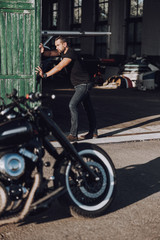 Obraz na płótnie Canvas Attractive adult biker closing door in garage