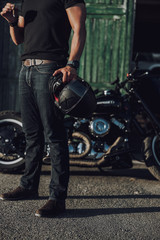 Fototapeta na wymiar Caucasian biker with cigar and helmet standing near motorcycle