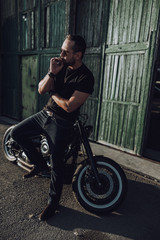 Fototapeta na wymiar Caucasian attractive guy with cigar standing near motorcycle