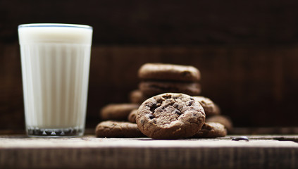 glass of milk cookies with chocolate chips on the background of wooden boards