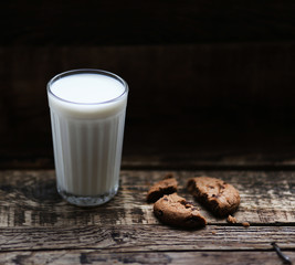 glass of milk cookies with chocolate chips on the background of wooden boards