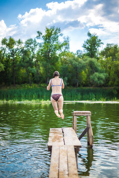 A beautiful woman jumping into the water from a pier.