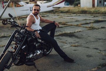 Fototapeta na wymiar Adult biker is resting on his black motorbike