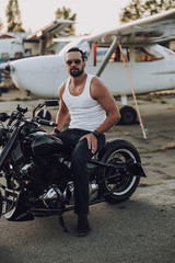 Fototapeta na wymiar Handsome motorcyclist is sitting on black motorcycle