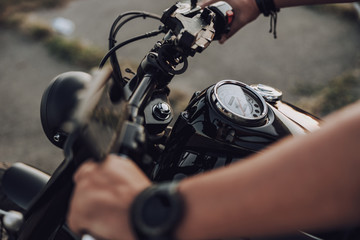 Fototapeta na wymiar Close up of male arms on motorbike wheel