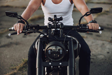 Man in t-shirt sitting on his motorbike outdoors