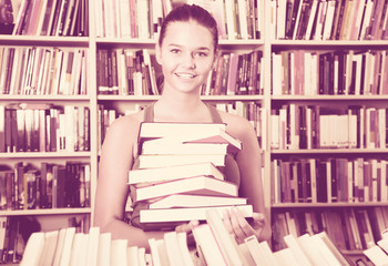 brunete girl chose a lot of books in university library