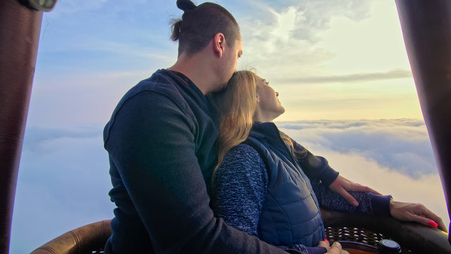 Adventure love couple on hot air balloon watermelon. Man and woman kiss hug love each other. Burner directing flame into envelope. Happy people.