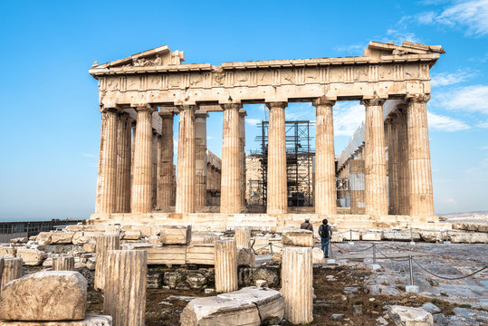 Parthenon on Acropolis hill, Athens, Greece. It is a top landmark of Athens. Ancient Greek ruins in Athens center in summer. Tourists look at the famous temple, remains of classical Athenian culture.