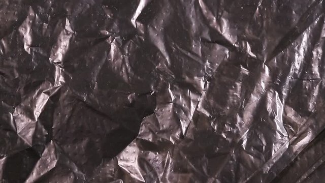 crumpled black polyethylene rotates slowly. abstract moving background
