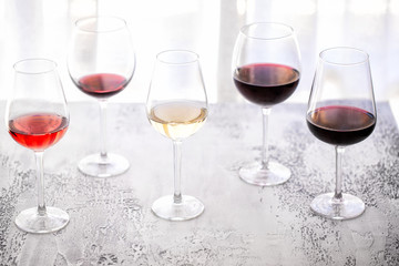Glasses with different wine bordeaux, red, rose  and white on white background. Beautiful wine variety concept.